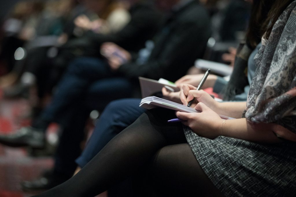 Audience prenant des notes lors d'une conférence de presse