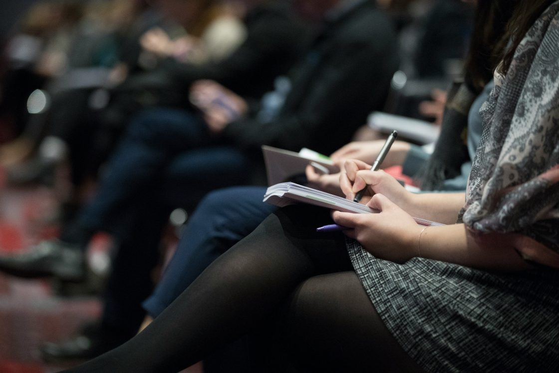 Audience prenant des notes lors d'une conférence de presse
